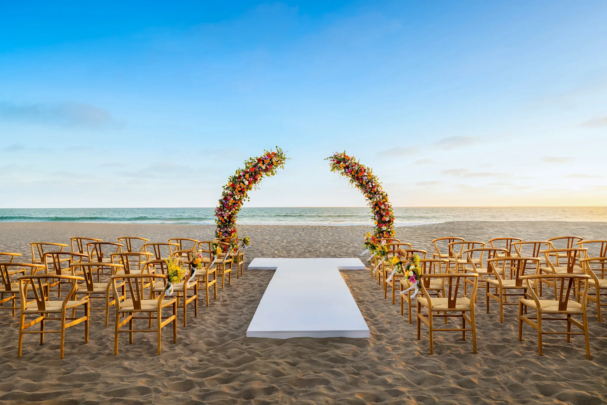 Beach wedding ceremony setup with floral arch and aisle on the sand at Dreams Estrella del Mar Mazatlán