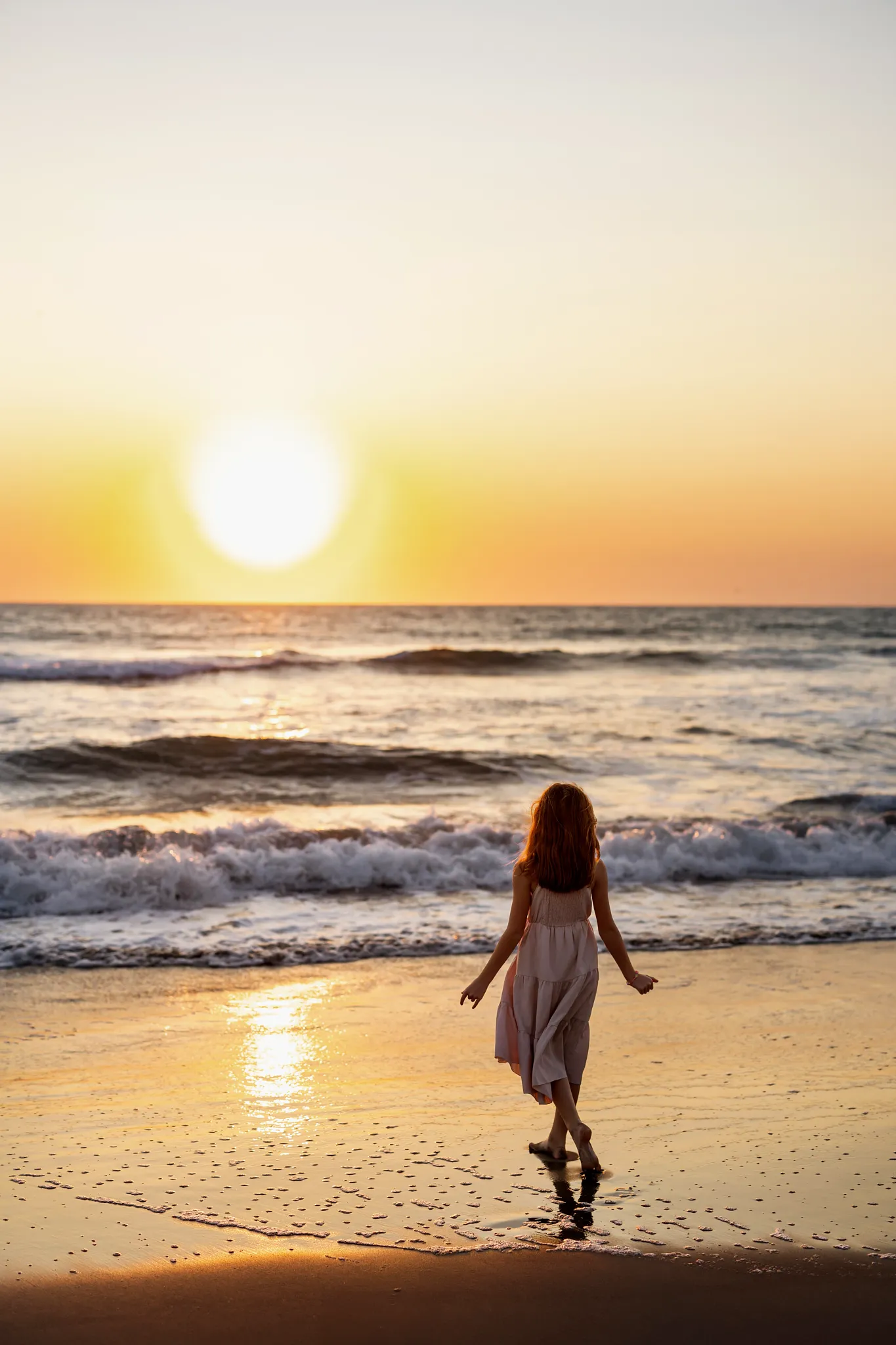 Young girl walking along the beach at sunset near Dreams Estrella del Mar Mazatlan Golf & Spa Resort.