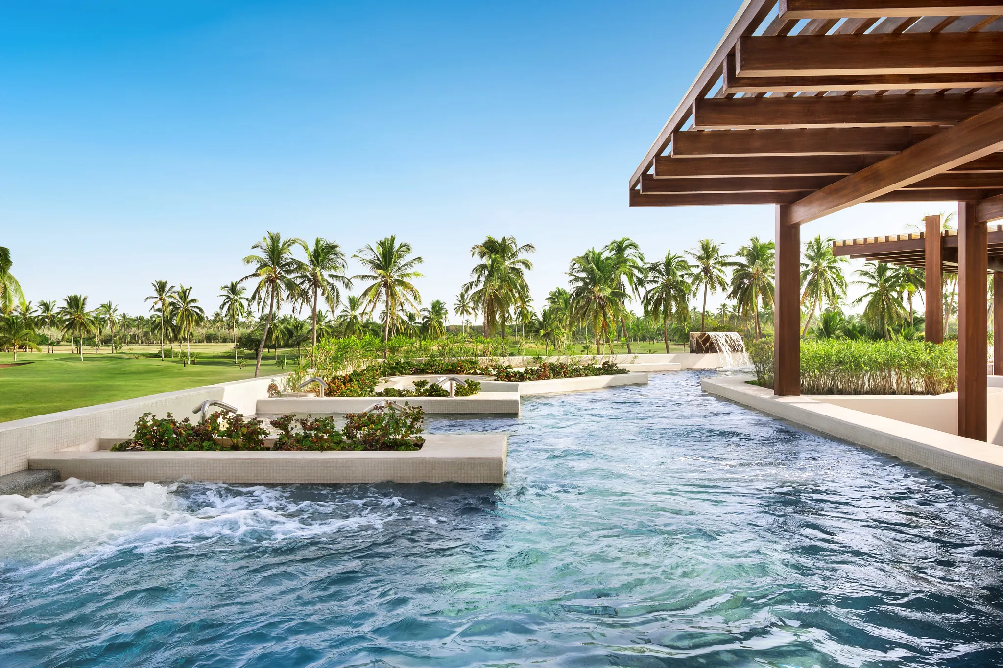 Outdoor hydrotherapy circuit with flowing pools and palm trees at Dreams Estrella del Mar Mazatlan Golf & Spa Resort spa.