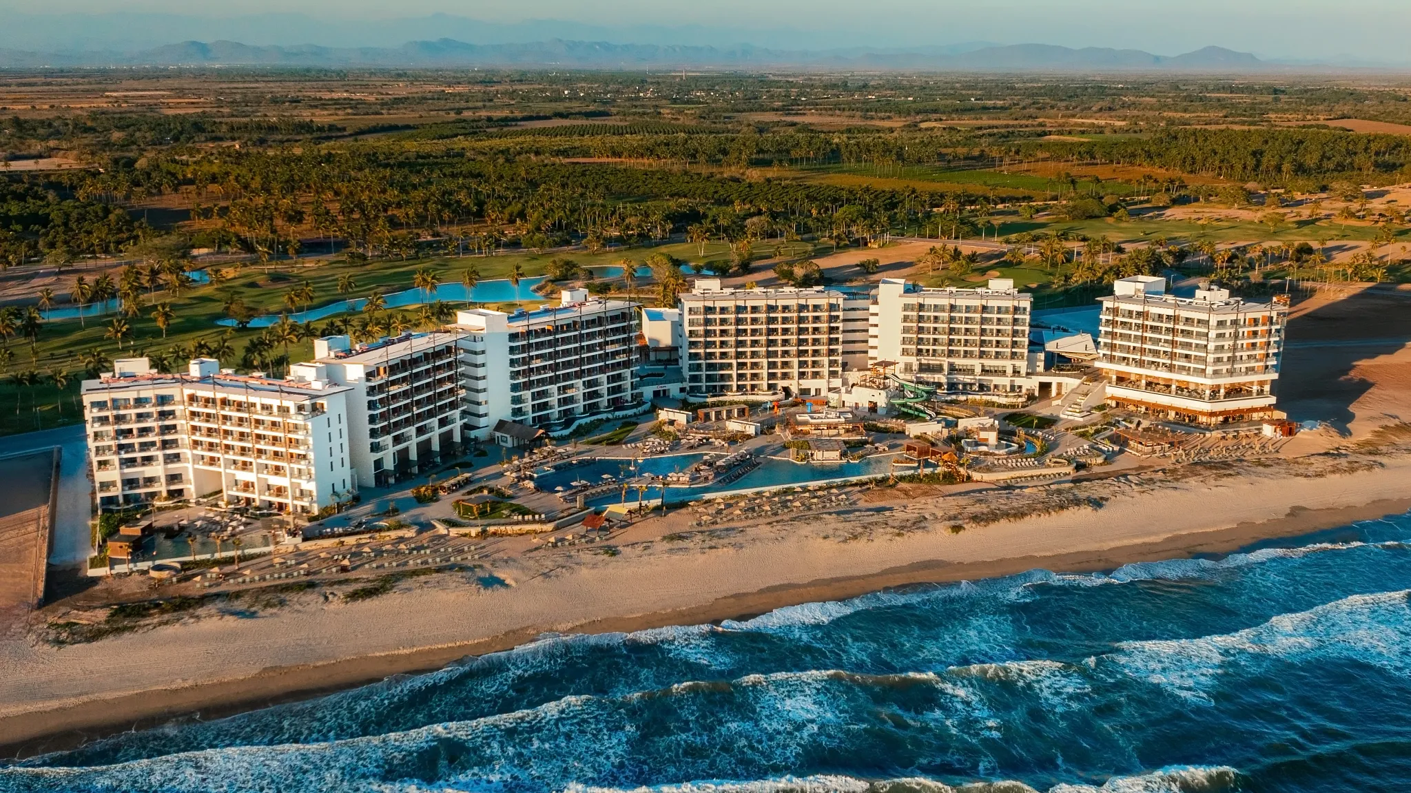 Aerial view of Dreams Estrella del Mar Mazatlan Golf & Spa Resort along a wide beachfront on the Pacific Ocean.