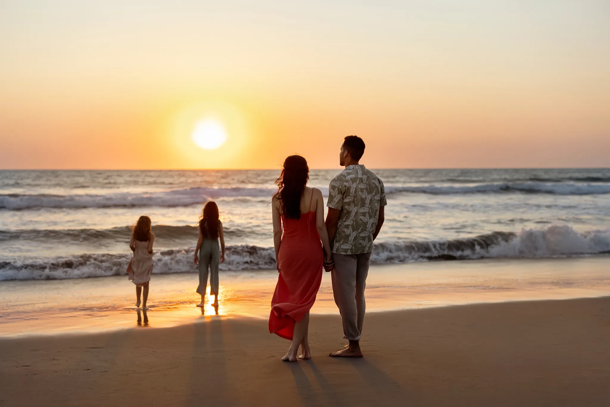 Parents watching their children play by the ocean at sunset at Dreams Estrella del Mar Mazatlan Golf & Spa Resort.